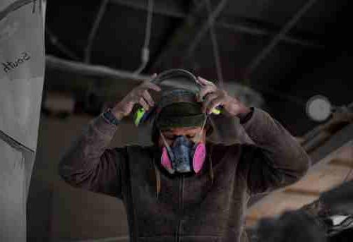 Artist Jason Quigno puts on a protective mask in his studio