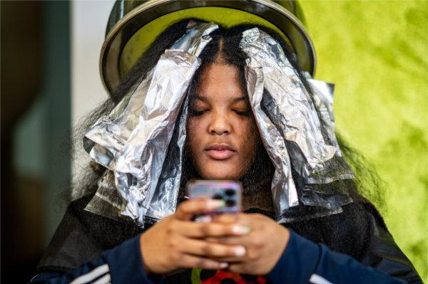 SeLaih Artis sits under a hair dryer with foil on her hair during a treatment