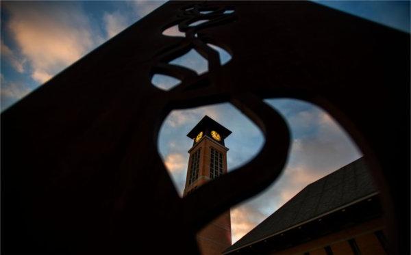 日出时，透过金属雕塑的形状可以看到钟楼. 