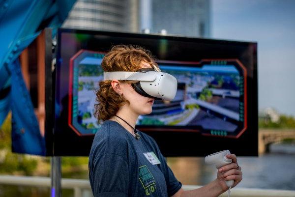一个人站在屏幕前通过VR头显观看.