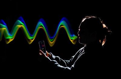 photo illustration of person holding cell phone, sound waves coming from mouth