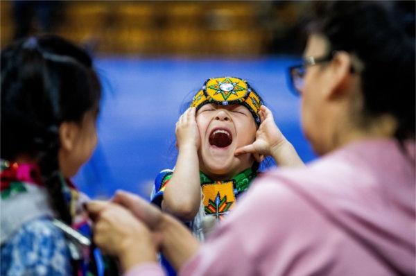 Adrian Pitawanakwat-Warner, 4, center, tries to make his sister laugh while she was getting her hair done by their mother during Grand Valley&rsquo;s 23rd annual &ldquo;Celebrating All Walks of Life&rdquo; Pow Wow April 13.