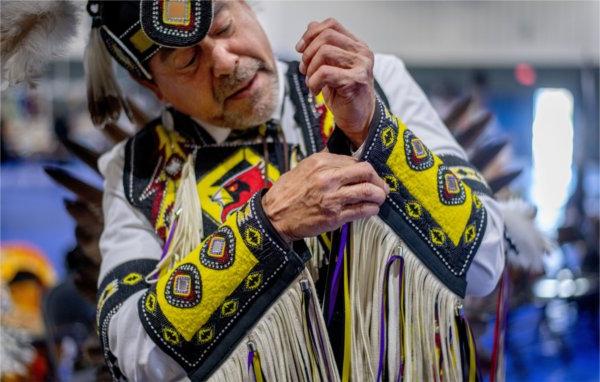 Greg Morsaw puts on his regalia for the men's northern traditional dance during the 23rd "Celebrating All Walks of Life" Pow Wow April 13.