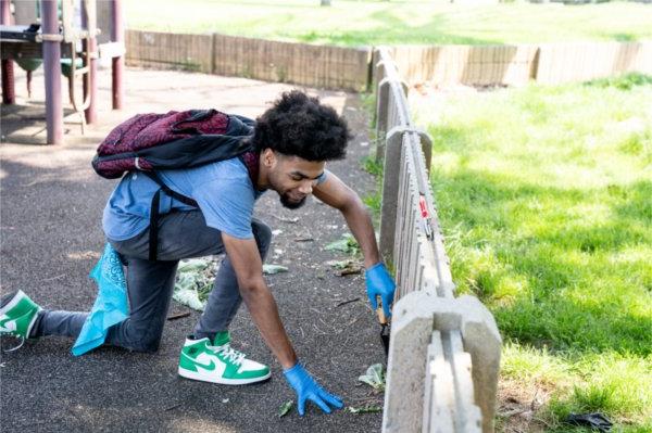一名来自底特律大学预科科学与数学高中的学生正在百丽岛公园操场上拔草.