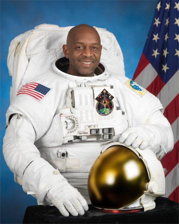 A person in an astronaut uniform smiles for the camera.