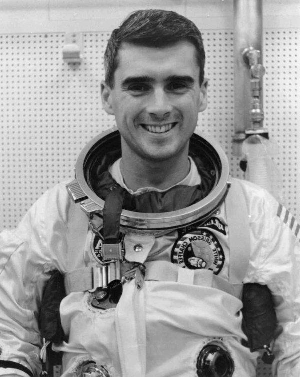 A person in an astronaut uniform smiles while posing for the camera.