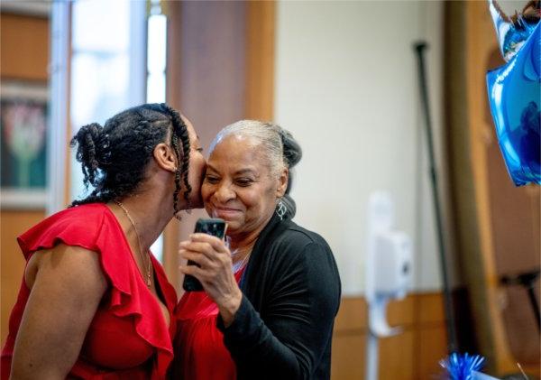Love Jordan, right, kisses her mom, Emma Howard, left, 5月13日，在塞德曼中心举行的密歇根资深企业家实验室最后一次推介活动中，她为自己的企业Loving Embrace做了宣传.