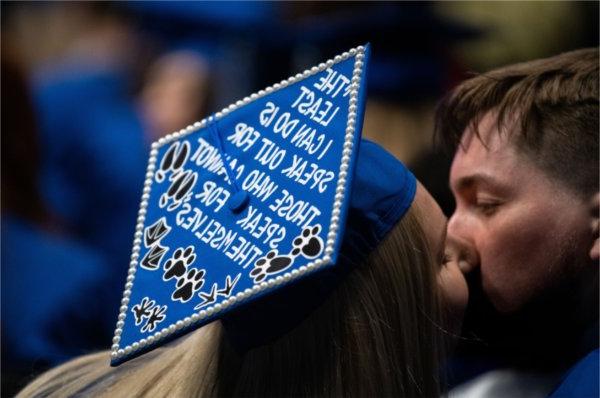 两个毕业生接吻，一个戴着学位帽. 