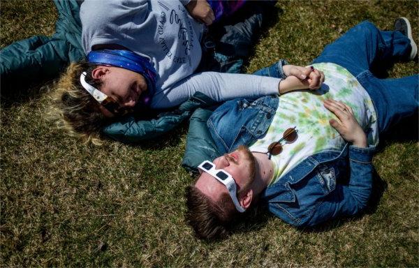  两名学生戴着防护眼镜手牵着手观看日食.