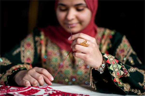 Aseel Ayesh sews a stitch into her tapestry.