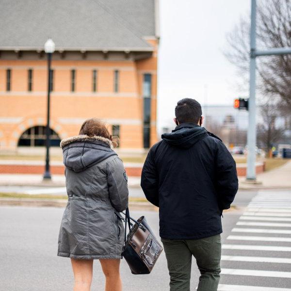 Two students cross the street in front of Secchia Hall on the Pew Grand Rapids Campus.