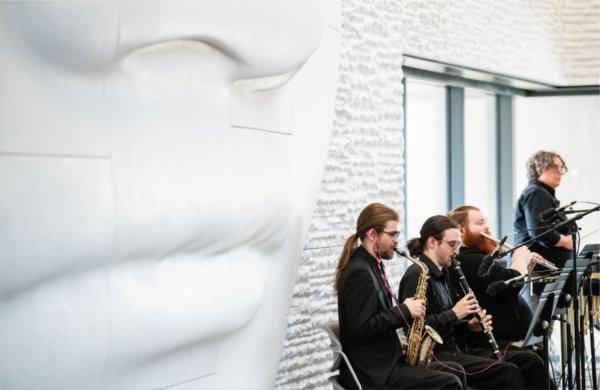  Musicians play in front of a large face sculpture. 